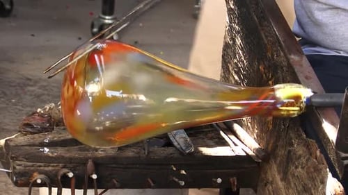 Detail of how a blown glass vase is shaped by a craftsman.