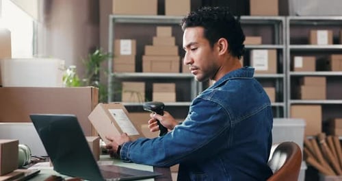 Man Scanning Package in Warehouse and Using Laptop