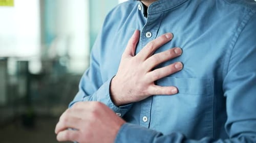 Close up. Male hands holding massaging chest. Mature businessman in a blue shirt has a heart attack