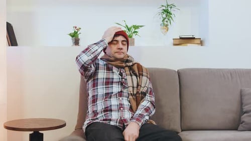 Adult Rubbing Head and Chest Wearing Scarf and Hat