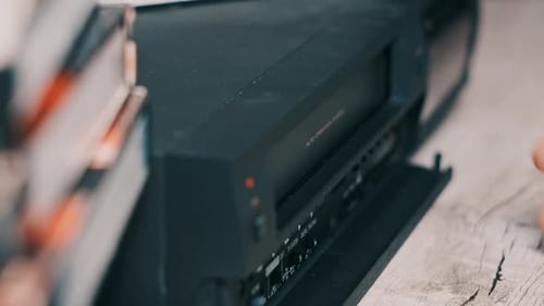 Hand Inserts VHS Tape Into VCR Player