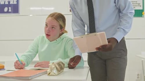 Teacher Helping Student with Assignment in Classroom