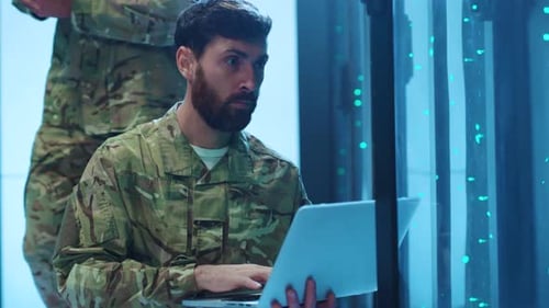 Ein Soldat benutzt gerade einen Laptop in einem Serverraum