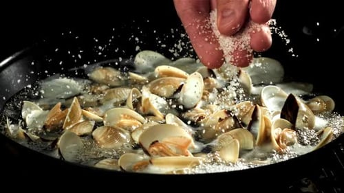 Le cuisinier ajoute du sel à la vongole fraîche filmée par une caméra à haute vitesse à 1000 images par seconde