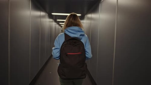 Una mujer con una mochila embarca por el pasillo del aeropuerto. El equipaje facturado solo es de mano