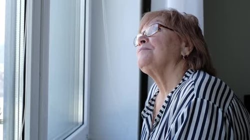 Senior Woman Gazing Out Window at Home
