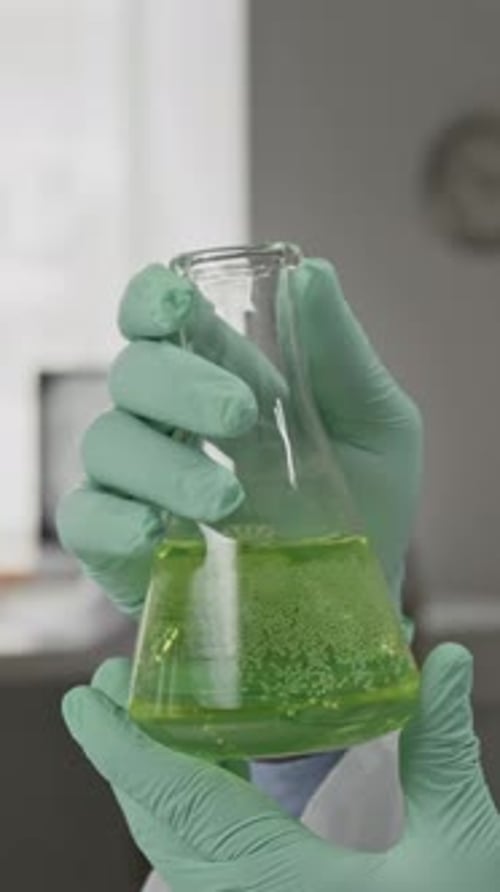 Close-up of Unrecognizable Scientist Scrutinizing Liquid-Filled Flask in Lab