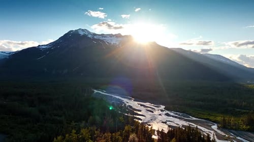 Bright sun dazzles the scenery from behind the high mountain.