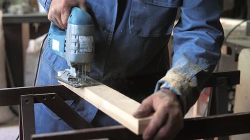 Woodworker Cutting Lumber With Jigsaw in Workshop