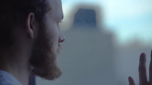 Sad guy near a window. Anxiety. Loneliness. Social distancing.