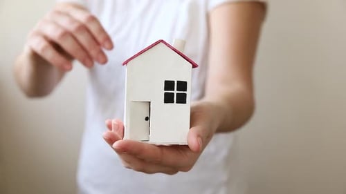 Woman Hand Holding Toy Model House Isolated on White Background