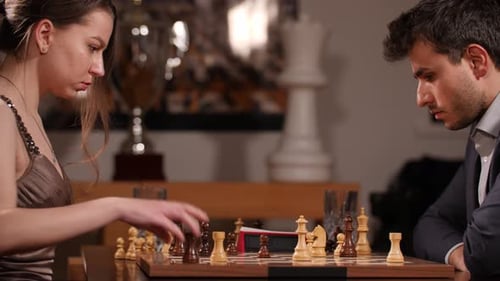 Das Weibchen bewegt ihren schwarzen Turm über das Schachbrett und drückt den Timer, während der Geschäftsmann