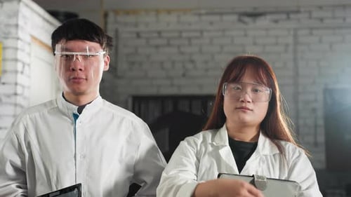 Technicians Holding Tablets and Adjusting Safety Glasses in Automotive Workshop