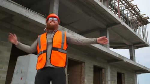 Alegre construtor de barba ruiva dançando, pulando alto de entusiasmo alegre, ocioso negócio bem-sucedido, tendo
