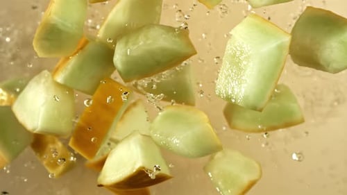 Melonenstücke fliegen auf hellem Hintergrund, gefilmt mit einer Hochgeschwindigkeitskamera mit 1000 Bildern pro Sekunde