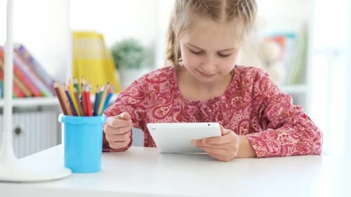 Girl Using Tablet at Table Indoors
