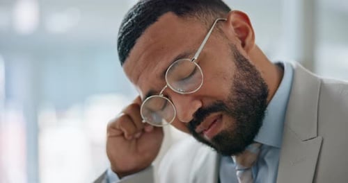 Man in Suit Removes Eyeglasses in Office
