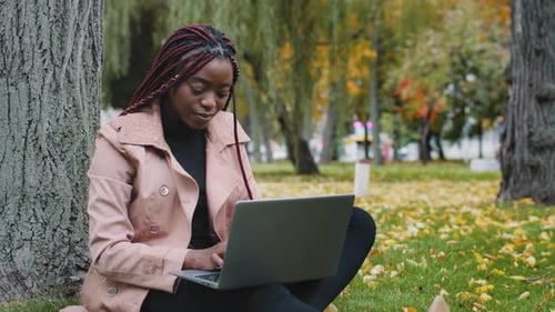 Young Attractive Stylish Female Freelancer Student Sitting in Park Typing on Laptop Working or