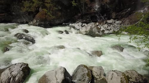 An einem strahlend sonnigen Frühlingstag fließt eine Flussströmung durch das Tal rund um die glatten Felsen