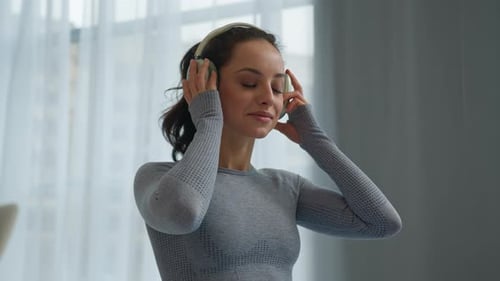 Woman Puts On Headphones and Uses Phone