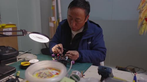 Man Assembles Small Drone at Indoor Workspace