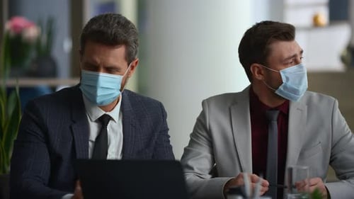 Multi ethnic business team discussing marketing sales wearing face masks in corporate office