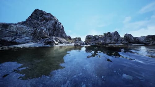 Rocky Shoreline Reflecting in Tranquil Water Under a Clear Blue Sky