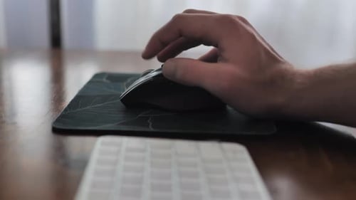 Hand Clicking Black Computer Mouse on Desk