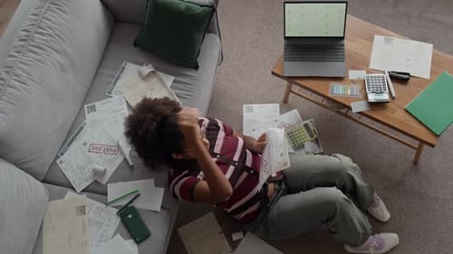 Concerned Woman among Overdue Bills with Laptop Managing Finances at Home