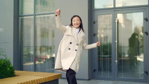 Cheerful happy business woman dancing walk the city street background a modern office building