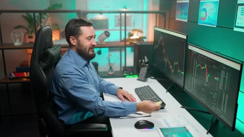 Man Holding Gold Coin in Office Analyzing Charts
