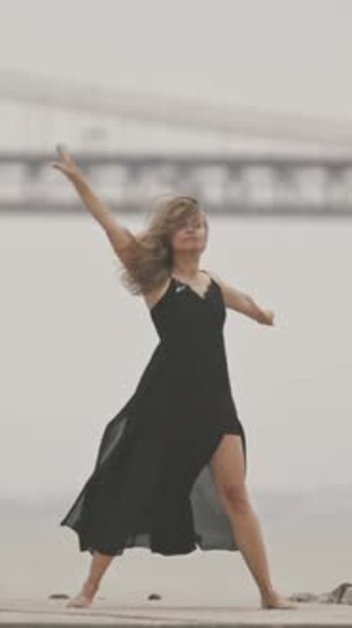 A Woman in Black Dress Dancing Ballet on the Pier