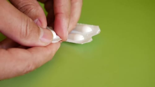 Hand Opens a Packaged Suppository