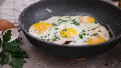 Golden Yolk Eggs with Parsley in Frying Pan