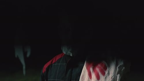 Menacing Masked Figure with Bloody Knife in Dark