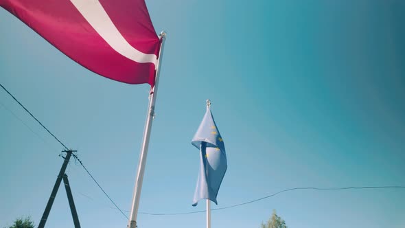 Latvian and European Union flags wave gracefully in slow motion against ...