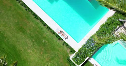 Aerial view of woman sunbathing lying on edge of pool. Senator Puerto Plata Spa Resort