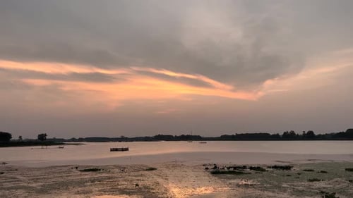 The golden sun dips below the horizon, casting a warm glow over the serene sunset lake.