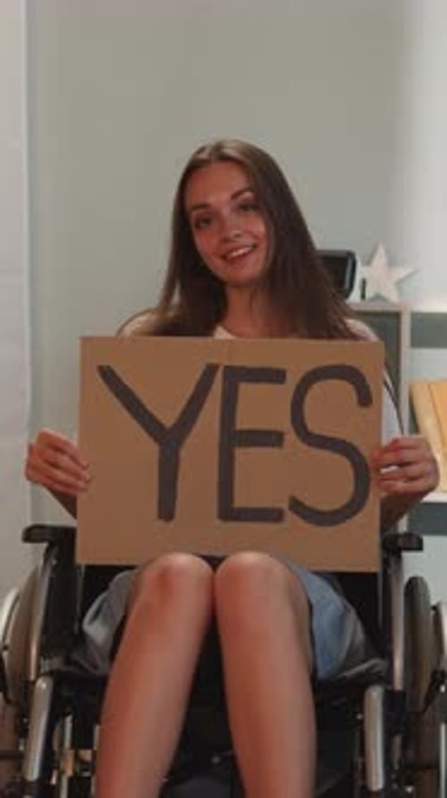 Smiling Woman in Wheelchair Holds 'Yes' Sign