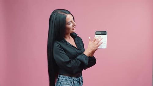 Woman Presents Calculator With Totals on Pink Backdrop