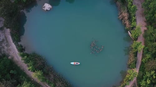Man Lying on SUP Surfboard on Blue Lake Surface