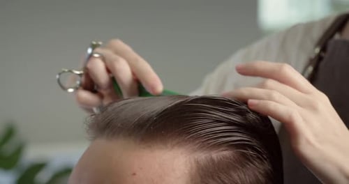 El peluquero moja el cabello con un spray y lo peina Un hombre elegante está sentado en la barbería