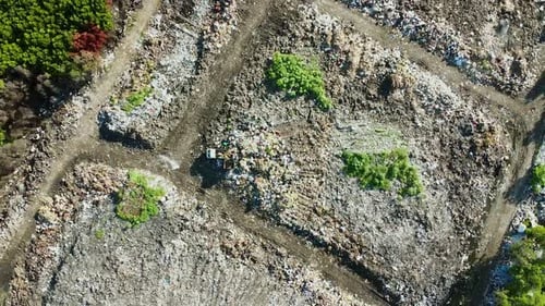 Aerial top view of huge landfill pile of dump and trash within mangroves trees and houses in Bali, I