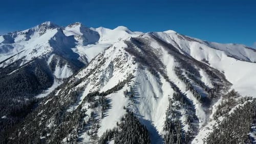 Air flight through mountain clouds over beautiful snow-capped peaks of mountains and glaciers.