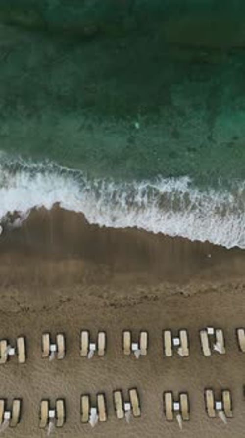Vertical Video Dawn's Embrace Aerial Gaze at a Beautiful Beach with Deserted Loungers