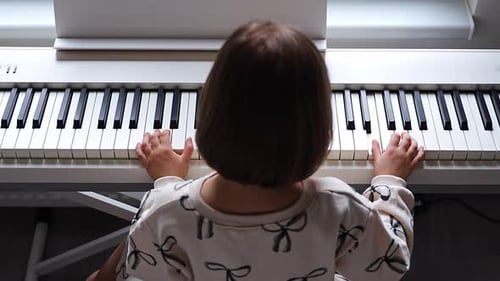 Child Plays White Electric Piano at Home