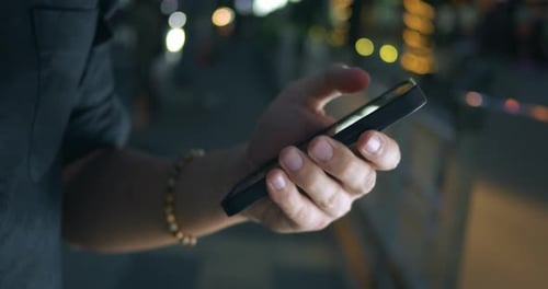 Focus on Male Hand Using Mobile Phone at Night City Street Background Close Up Man Holding Mobile