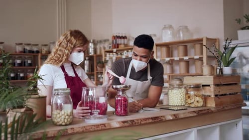 Colleagues Filling Jar by Dryed Raspberries and Talking in Zero Waste Shop
