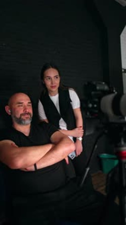 Studio scene shows man and woman near camera