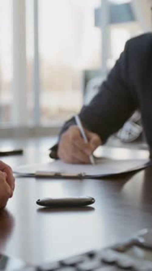 Man Signing Loan Agreement in Car Dealership Vertical